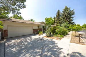 View of front of home with brick siding, concrete driveway, an attached garage, and a shingled roof