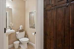 Half bath featuring toilet, tile patterned floors, and baseboards