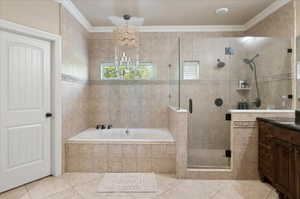 Full bathroom featuring tile patterned flooring, a garden tub, vanity, a shower stall, and ornamental molding
