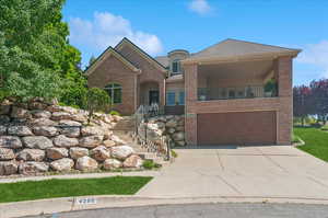 View of front facade featuring an attached garage, brick siding, concrete driveway, and stairway