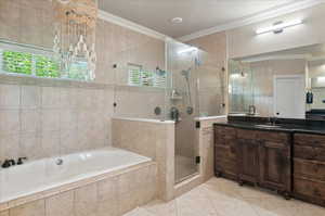 Bathroom featuring tile walls, crown molding, vanity, a garden tub, and healthy amount of natural light