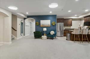 Kitchen with freestanding refrigerator, black microwave, light colored carpet, arched walkways, and recessed lighting