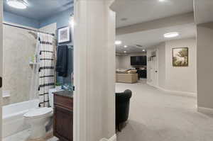 Bathroom featuring shower / tub combo, toilet, vanity, baseboards, and recessed lighting