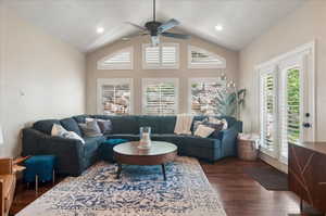 Living room with dark wood-style flooring, vaulted ceiling, and a ceiling fan