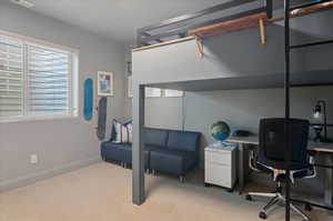 Bedroom with light carpet, a desk, and baseboards