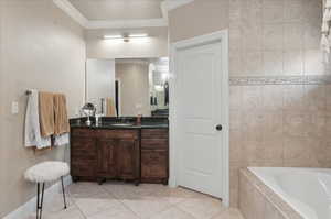 Full bath with crown molding, tiled bath, vanity, tile patterned flooring, and baseboards