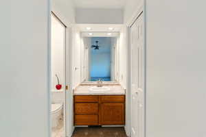 Bathroom featuring toilet, vanity, a closet, a ceiling fan, and recessed lighting