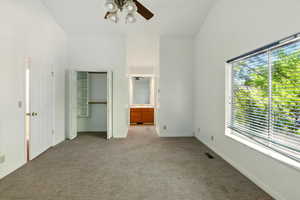 Unfurnished bedroom featuring light carpet, a closet, ensuite bathroom, baseboards, and ceiling fan