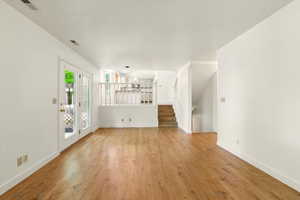 Unfurnished living room featuring light wood-style flooring, baseboards, and stairs