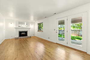 Unfurnished living room featuring light wood-style flooring, a fireplace, and baseboards