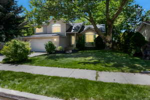 View of front of house with a garage, a front yard, and driveway