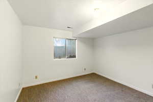 Carpeted spare room featuring baseboards