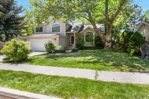 Tri-level home featuring a garage, a front lawn, concrete driveway, roof with shingles, and brick siding