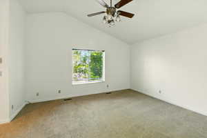 Empty room featuring light carpet, ceiling fan, baseboards, and high vaulted ceiling