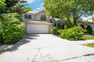 View of front facade with a garage, concrete driveway, brick siding, and a shingled roof