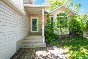 Doorway to property featuring brick siding and a wooden deck