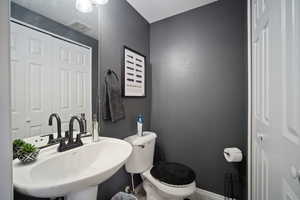 Bathroom featuring a sink, toilet, and baseboards