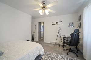 Bedroom featuring carpet flooring, baseboards, ceiling fan, and a desk