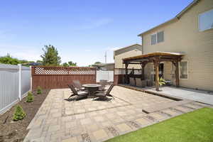 Fenced backyard with a fire pit, a pergola, and a patio