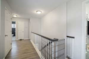 Hall featuring an upstairs landing, wood finished floors, and baseboards