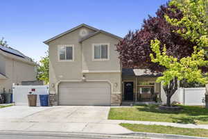 View of front of house with driveway, stucco siding, an attached garage, and stone siding