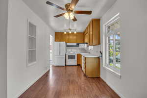 Kitchen with white appliances, a sink, dark wood finished floors, and baseboards