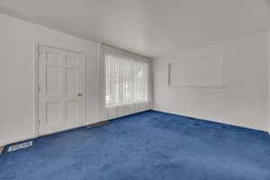 Spare room featuring dark colored carpet and baseboards