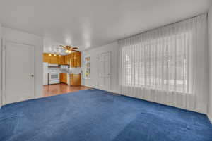 Unfurnished living room featuring carpet and ceiling fan