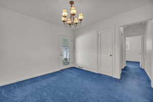 Unfurnished room with dark carpet, a chandelier, and baseboards