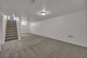 Below grade area with carpet floors, stairway, and baseboards