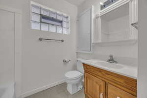 Full bathroom with vanity, tile patterned flooring, toilet, baseboards, and a tub