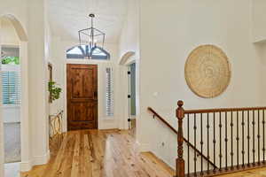 Foyer entrance featuring arched walkways, wood finished floors, and chandelier