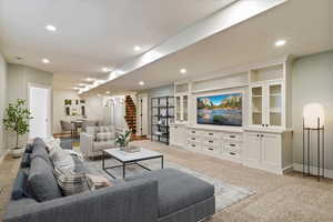 Virtually staged family room with built in entertainment center, light carpet, and recessed lighting