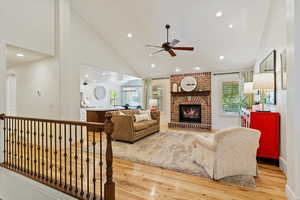 Living room featuring vaulted ceiling,light hardwood flooring, a beautiful fireplace, and recessed lighting