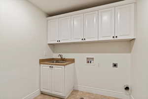 Washroom featuring hookup for an electric dryer, built in cabinetry and sink