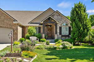 View of front of property featuring brick siding, a front lawn, roof with shingles, an attached garage