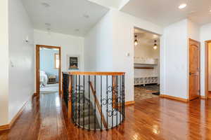Hallway featuring an upstairs landing, hardwood / wood-style floors, and baseboards