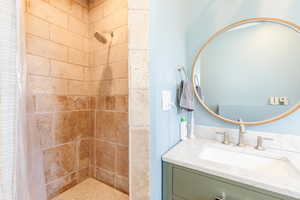 Bathroom featuring a tile shower and vanity