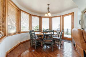 Dining area with dark wood-style flooring, a chandelier, and baseboards