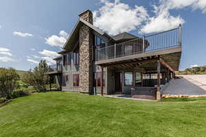Back of property with a hot tub, a yard, a chimney, and a deck