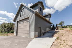 View of home's exterior featuring asphalt driveway, board and batten siding, and stairs
