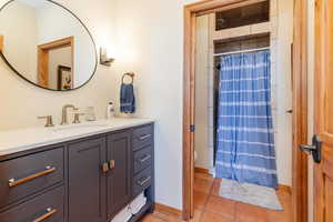 Bathroom with tile patterned floors, vanity, toilet, curtained shower, and baseboards