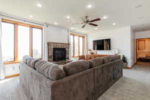 Living area with baseboards, light carpet, a fireplace, recessed lighting, and a ceiling fan