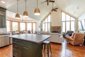 Kitchen with dishwasher, high vaulted ceiling, a kitchen island, a breakfast bar, and a ceiling fan
