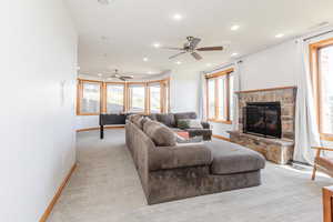 Living area with a ceiling fan, a stone fireplace, recessed lighting, baseboards, and plenty of natural light