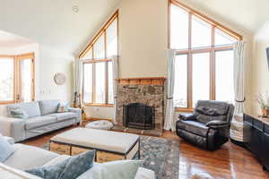 Living room with vaulted ceiling, a fireplace, and hardwood / wood-style floors