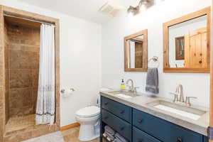 Full bath featuring double vanity, toilet, a tile shower, and tile patterned flooring