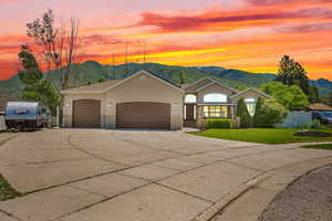 Single story home featuring concrete driveway, a mountain view, an attached garage, and stucco siding