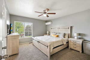 Updated carpeted bedroom featuring an AC wall unit and updated paint