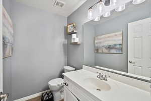 Half bathroom featuring toilet, vanity, and updated light fixture
